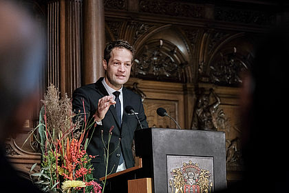 Der Preisträger Prof. Dr. Dr. Fabian Theis hält seine Dankesrede für den Erhalt des Hamburger Wissenschaftspreises. Theis steht hinter dem Rednerpult im großen Festsaal des Hamburger Rathauses.