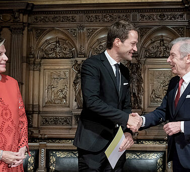 Der Akademiepr&auml;sident Prof. Dr. Edwin J. Kreuzer gratuliert Prof. Dr. Dr. Fabian Theis mit einem H&auml;ndesch&uuml;tteln. Eva-Maria Greve steht neben ihnen und schaut die beiden M&auml;nner l&auml;chelnd an