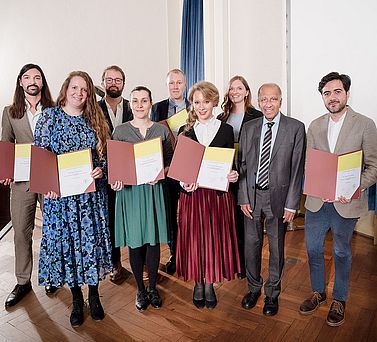 Die Young Academy Fellows bei der feierlichen Aufnahme am 16. Oktober 2025 mit Akademiepr&auml;sident Prof. Dr. Mojib Latif (von links): Dr. Pierre Sfendules, Dr. Katrin Kleemann, Dr. Jan S. Krause, Dr. Amra Jahic, Dr. Fabien Schultz, Dr. Carolin Gluchowski, Dr. Clara-Auguste S&uuml;&szlig; und Dr. Andr&eacute;s L&oacute;pez Rivera. Nicht auf dem Bild zu sehen ist Dr. Alica Repenning.