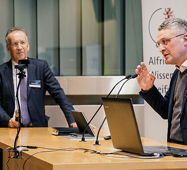 Prof. Dr. Dr. h. c. Lothar Wieler steht hinter dem Rednerpult und spricht zum Publikum. Links neben ihm steht als Moderator Prof. Dr. Ansgar Lohse.