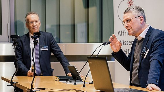 Prof. Dr. Dr. h. c. Lothar Wieler steht hinter dem Rednerpult und spricht zum Publikum. Links neben ihm steht als Moderator Prof. Dr. Ansgar Lohse.