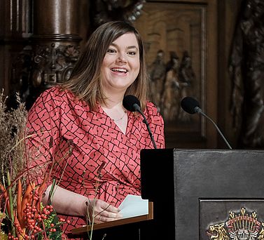 Wissenschaftssenatorin Katharina Fegebank steht hinter dem Rednerpult und schaut l&auml;chelnd in Richtung Publikum.