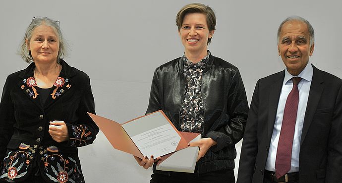 Die Preisträgerin Judith Niehaus hält die Urkunde für den Elise-Reimarus-Preis in den Händen. Niehaus steht zwischen Jurymitglied Prof. Dr. Eva Wilden und Akademiepräsident Prof. Dr. Mojib Latif. 