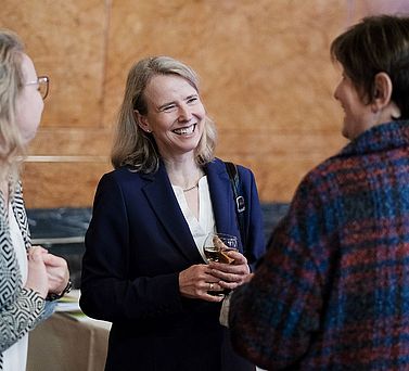 Die Gesch&auml;ftsf&uuml;hrerin der Akademie der Wissenschaften in Hamburg, Claudia Raap, steht l&auml;chelnd zwischen zwei Besucherinnen der Preisverleihung.