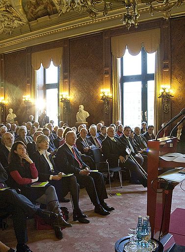 Eine Weitwinkel-Ansicht bei der Verleihung des Hamburger Wissenschaftspreises 2009 im Hamburger Rathaus. Der Erste B&uuml;rgermeister Ole von Beust steht rechts hinter dem Rednerpult, w&auml;hrend das Publikum links auf St&uuml;hlen sitzt.