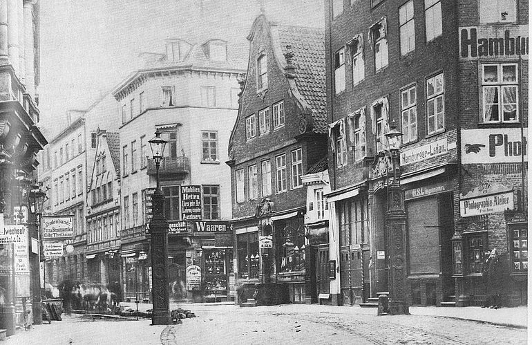 Blick vom Hamburger Stadtgebiet nach Altona, um 1880: Das Foto zeigt das Nobistor als Grenz&uuml;bergang zwischen den beiden St&auml;dten. Zwei gusseiserne Laternenmasten rahmen die Fahrbahn; der rechte ist bis heute erhalten. Im Hintergrund verl&auml;uft die Reichenstra&szlig;e (fr&uuml;her: Reichengasse), von rechts m&uuml;ndet die Gro&szlig;e Freiheit ein, erkennbar am Ladenschild &bdquo;Waaren&ldquo; an der Ecke.